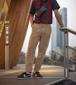 Low section of man standing on railing