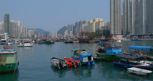 Boats moored in sea against buildings in city