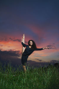 Woman standing on field against sky during sunset