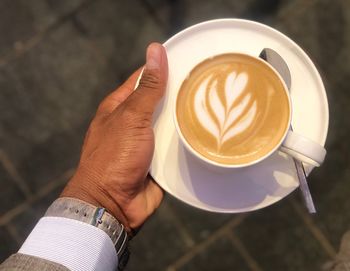 High angle view of hand holding coffee cup