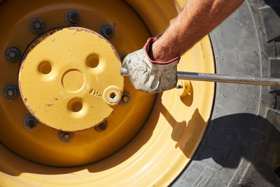 Cropped image of man arm with working glove preparing big excavator tire for replace 