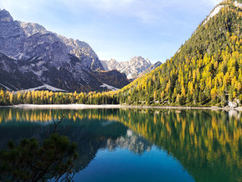 Natural landscape of braies lake with green trees, lake with reflection and mountain with snow