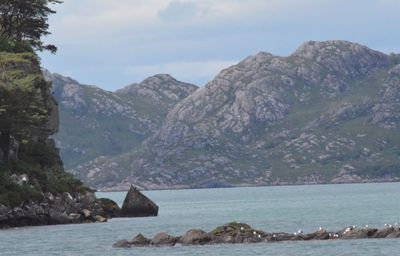 Scenic view of sea and mountain against cloudy sky