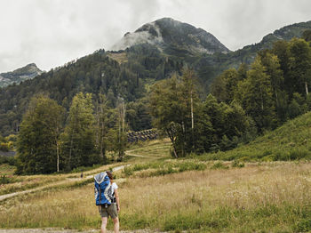 Rear view of woman with big backpack walking on mountain hiking nature, healthy active lifestyle