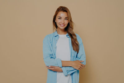 Portrait of young woman standing against pink background