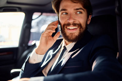 Portrait of young man using mobile phone in car