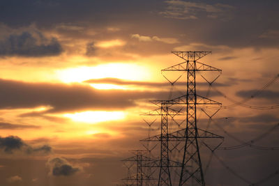 Low angle view of silhouette electricity pylon against sky during sunset