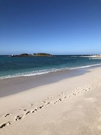 Scenic view of beach against clear blue sky