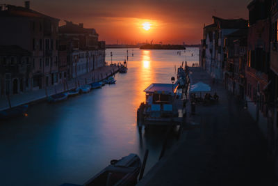 Sunset at a canal in venice italy with reflection and water movement captured with long exposure.
