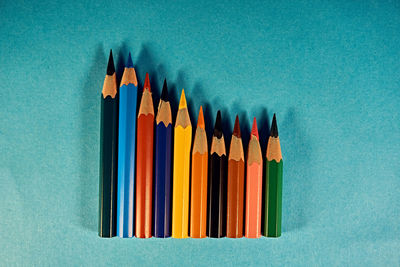 Close-up of multi colored pencils on table against blue background