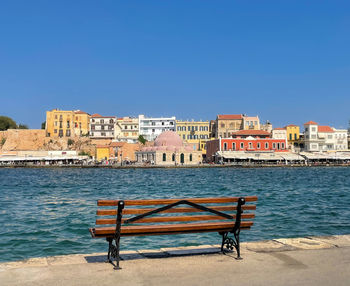 Buildings by canal against clear blue sky