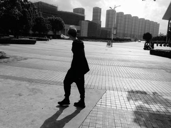 Rear view of woman walking on sidewalk in city
