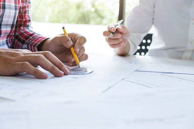 Midsection of architects working while on table in office