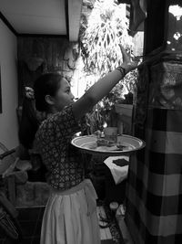 Beautiful balinese girl's face seen from the side doing hindu prayers, in black and white style