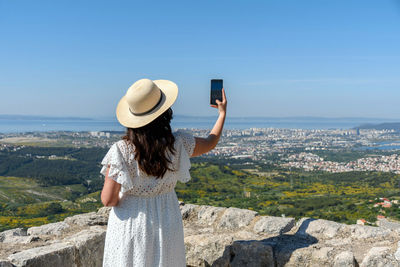 Rear view of woman taking photos of cityscape of split in croatia