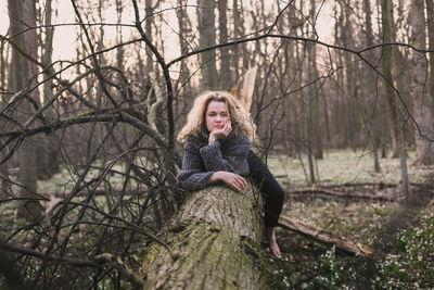 Blonde woman sitting on large fallen tree scenic photography