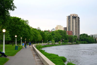 Surface level of footpath by river in park against clear sky