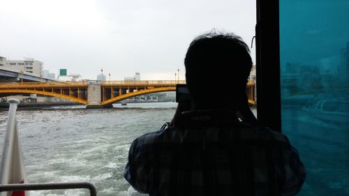 Rear view of woman on bridge over river against sky