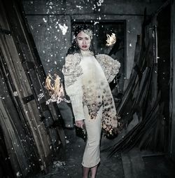 Portrait of beautiful young woman wearing burning fairy costume while standing in abandoned room