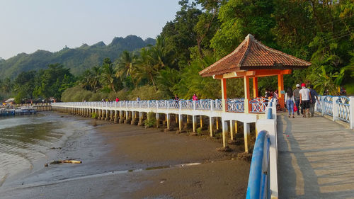 Built structure by trees and plants against sky