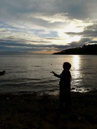 Silhouette man standing on beach against sky during sunset