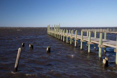 Wooden pier on sea against clear sky