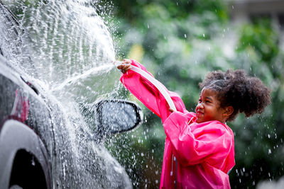 Side view of girl with pink petals in water