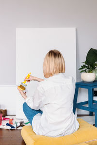 Rear view of woman sitting on table at home