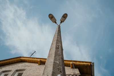 Low angle view of cross by building against sky