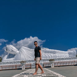 Man standing on railing against blue sky