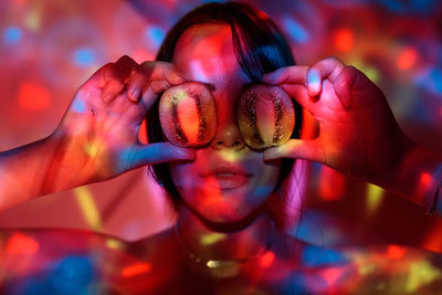 Colorful lights falling on young woman holding halved figs