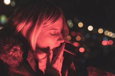Close-up of young woman smoking cigarette at night