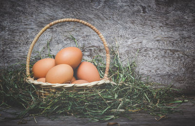 Close-up of eggs in wicker basket with grass by plant on table