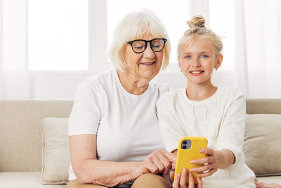 Portrait of young woman using mobile phone while sitting on sofa at home