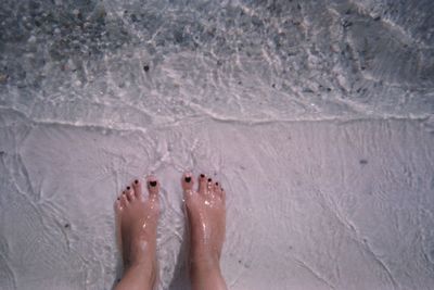 Low section of woman standing on sand at beach