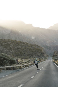 Full length of woman skateboarding on road against mountains