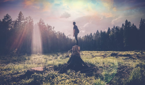 Man standing on field against sky during sunset