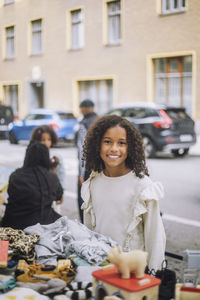 Smiling girl with curly hair neat stall at flea market