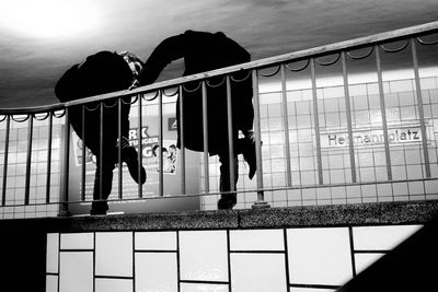 Silhouette man and woman standing by railing