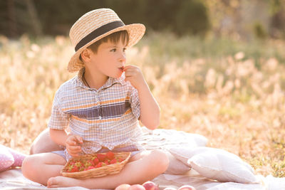 Cute boy wearing hat eating fruit