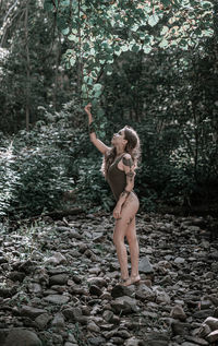 Woman standing by tree in forest