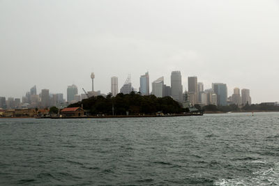 Sea by cityscape against clear sky