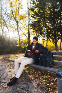 Portrait of young man sitting on land against trees