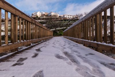 Footbridge over canal amidst buildings against sky during winter