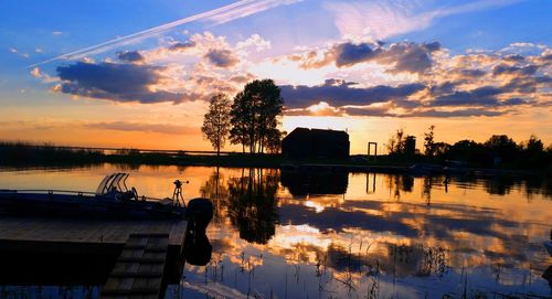 Reflection of clouds and silhouette trees in lake during sunset