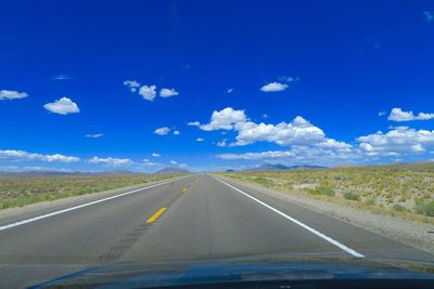 Road by landscape against sky seen through car windshield