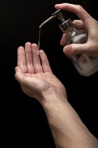 Midsection of person holding cigarette against black background