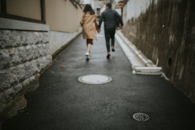 Rear view of couple running on road