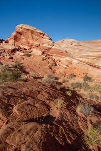 Rock formations on landscape against clear blue sky