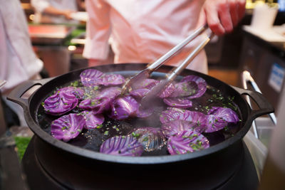 Midsection of man cooking cabbage in pan